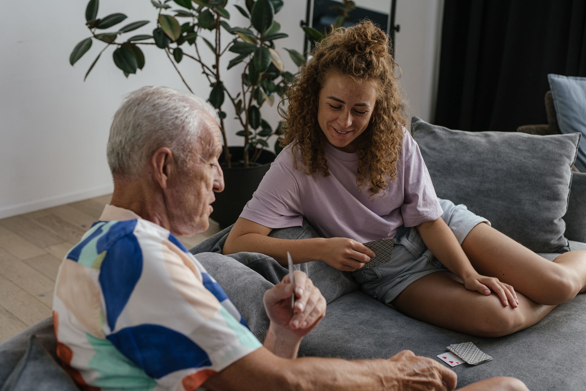 An older man and a younger woman enjoying a card game at home. Illustrative photography.